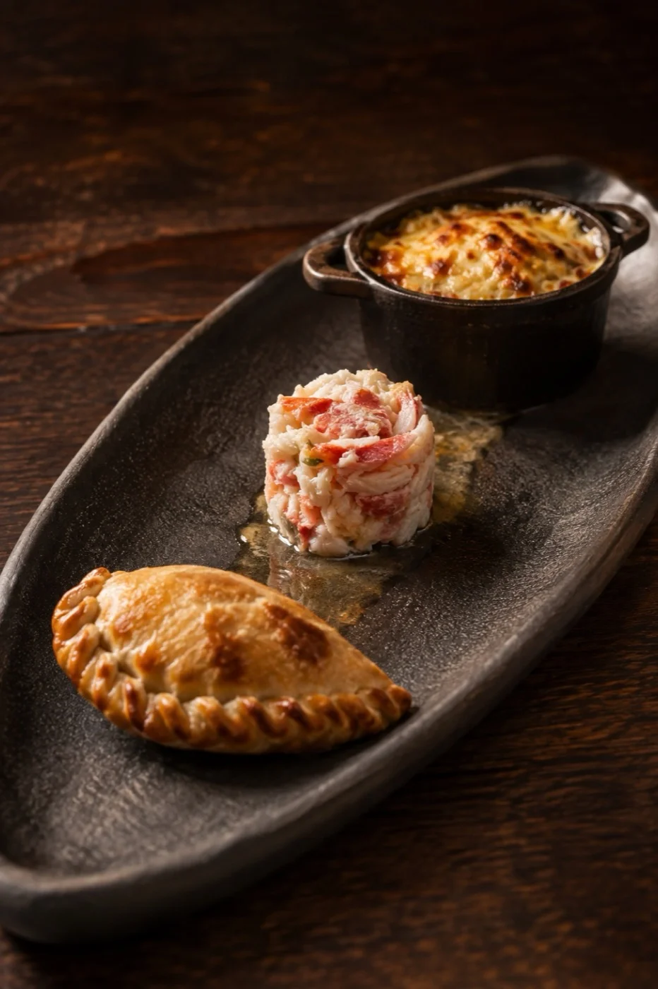 Board with a king crab empanada, king crab au naturel and gratinated king crab chupe