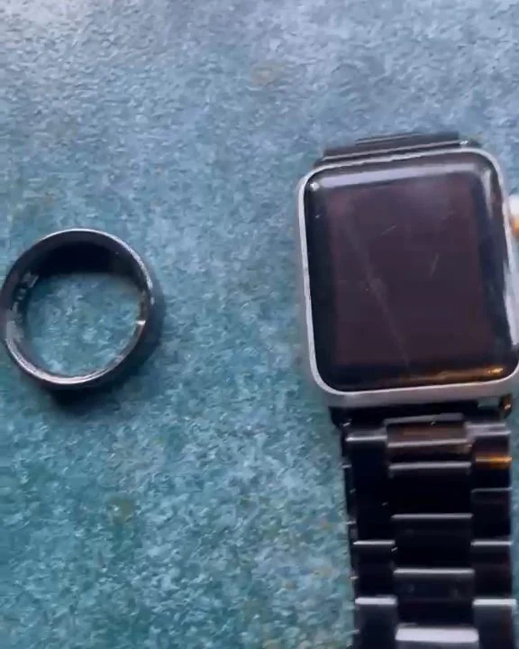 The house's biosensor ring beside a smartwatch on a stone table